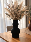 Schwarze Strukturvase Liora mit Trockenblumen auf einem Holztisch; Blumen nicht enthalten.