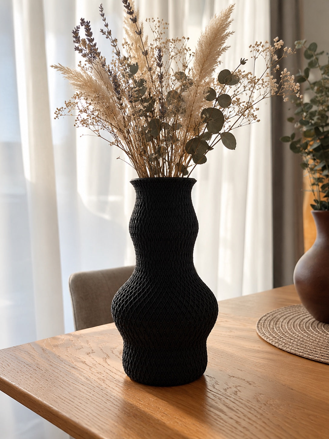 Liora in Schwarz mit Trockenblumen im Wohnambiente; Dekoration nicht enthalten.